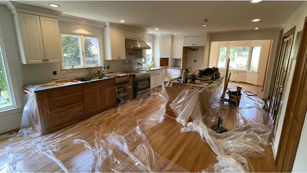 A residential kitchen prepared for remodeling with protective floor coverings